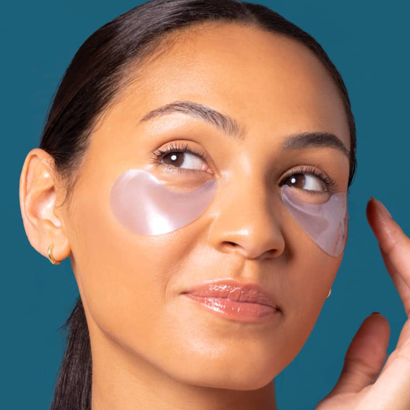 Woman wearing eye patches with a teal background