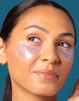 Woman wearing eye patches with a teal background
