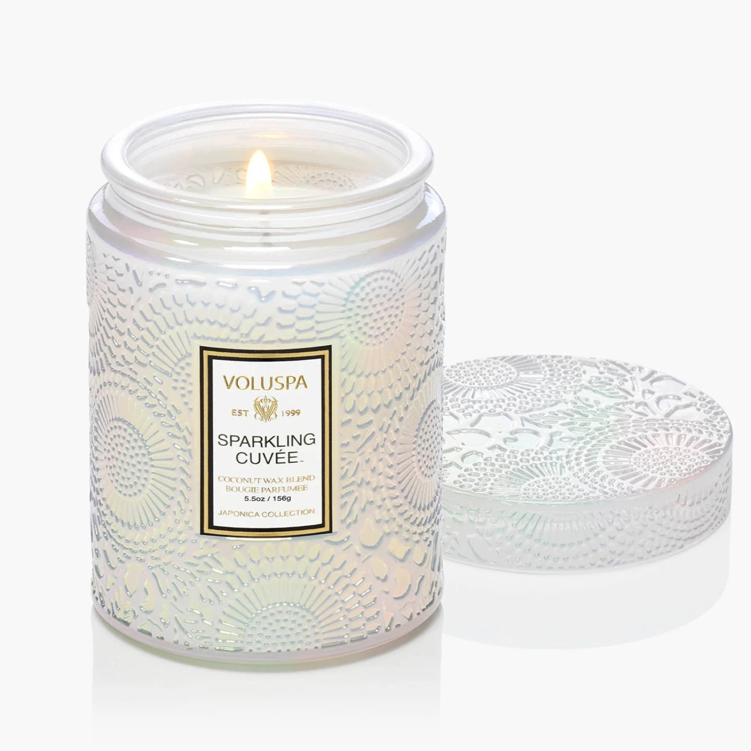 White candle in a decorative jar with a visible brand label on a white background