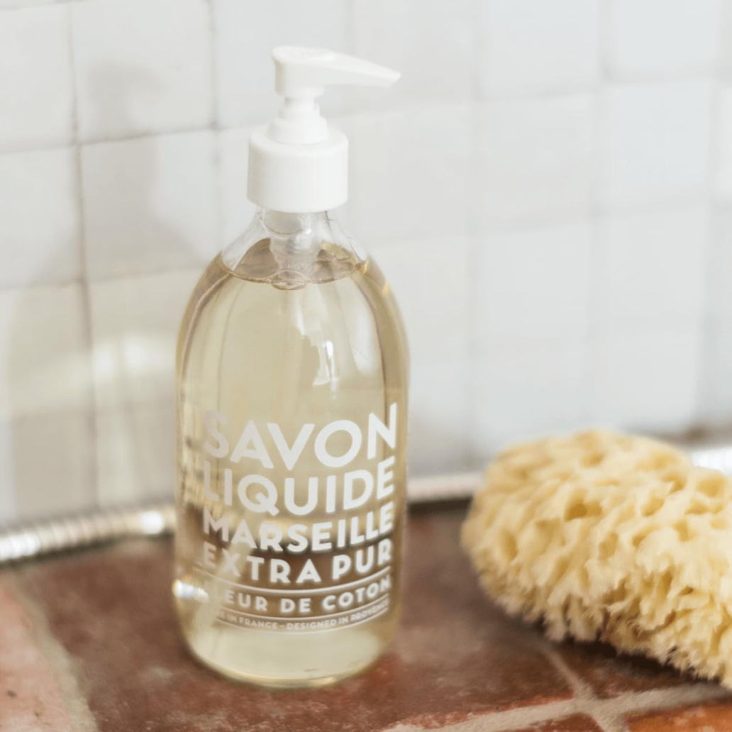 Bottle of Savon Liquide Marseille Extra Pur soap on a kitchen counter with a sponge in the background.