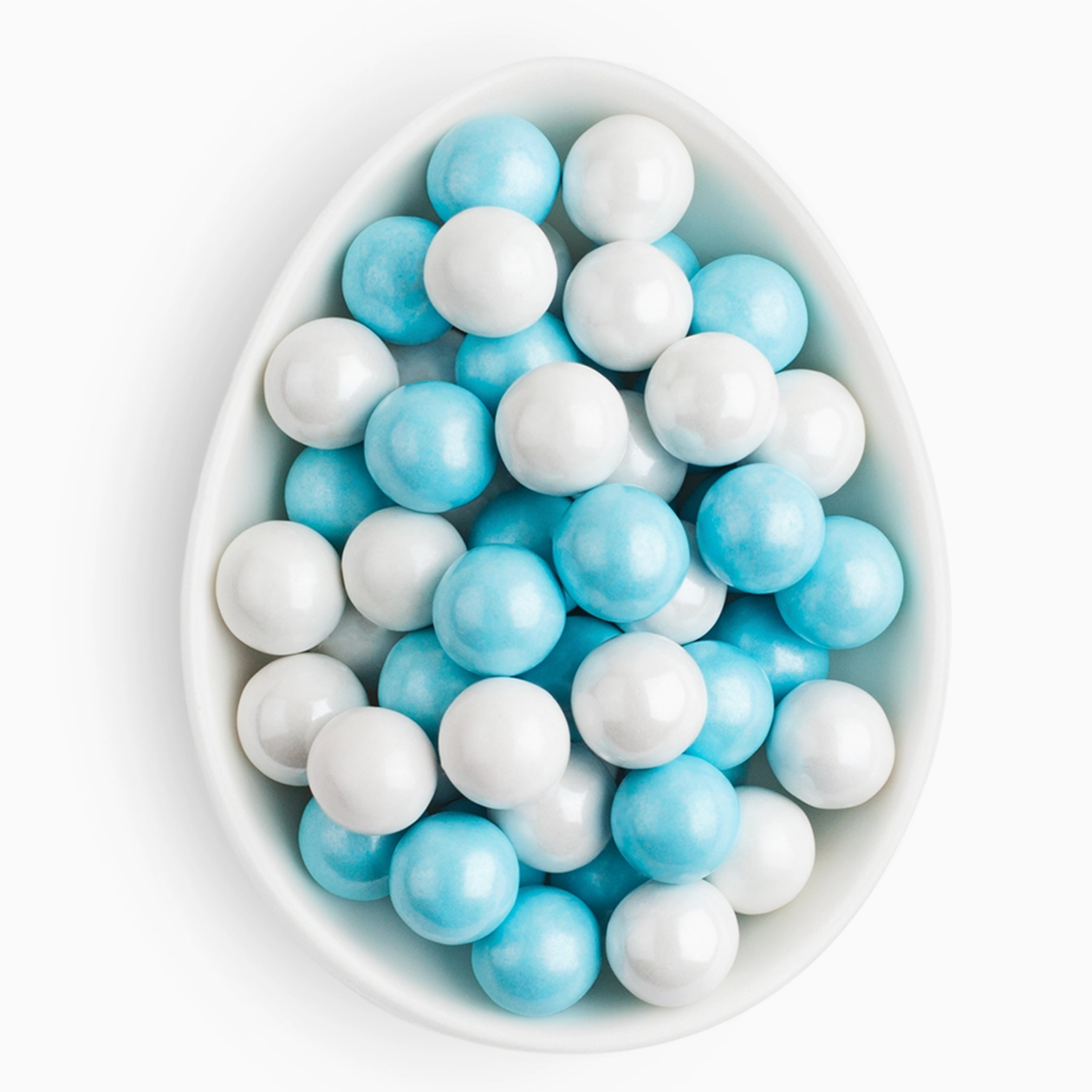 White and blue round candies in a white bowl on a white background