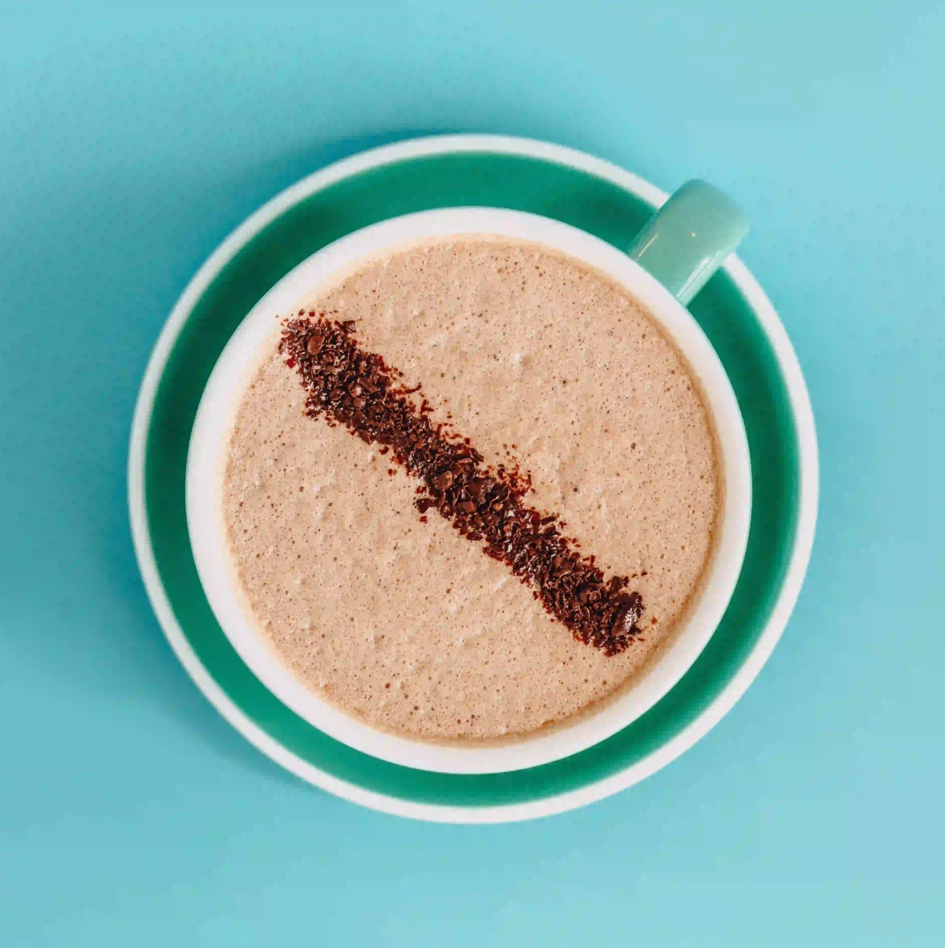 Cup of coffee with a heart shape made from coffee grounds on a blue background