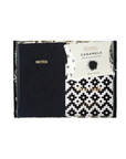 Black notebook with 'NOTES' text and a white caramels packaging with black and white pattern on a white background