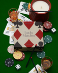 Candle, playing cards, poker chips, dice, and 'Lucky Matches' box on a green surface