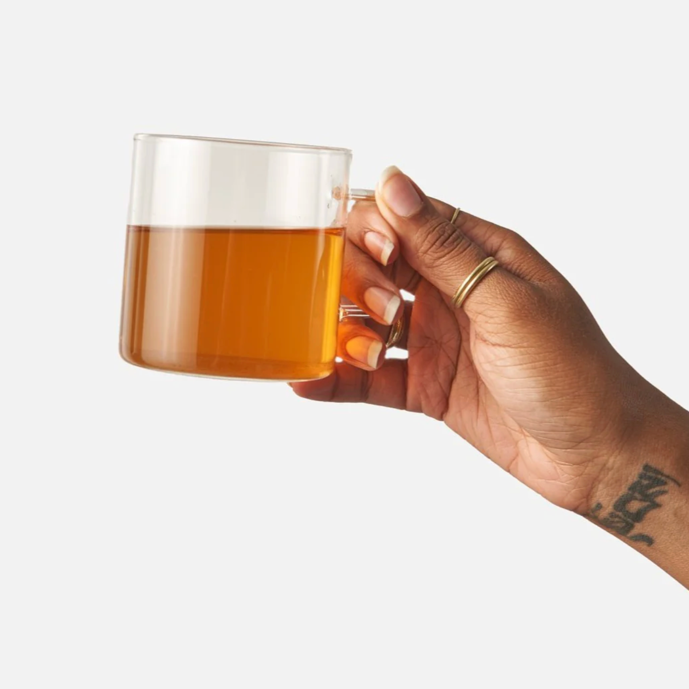 Hand holding a glass mug with amber liquid against a white background