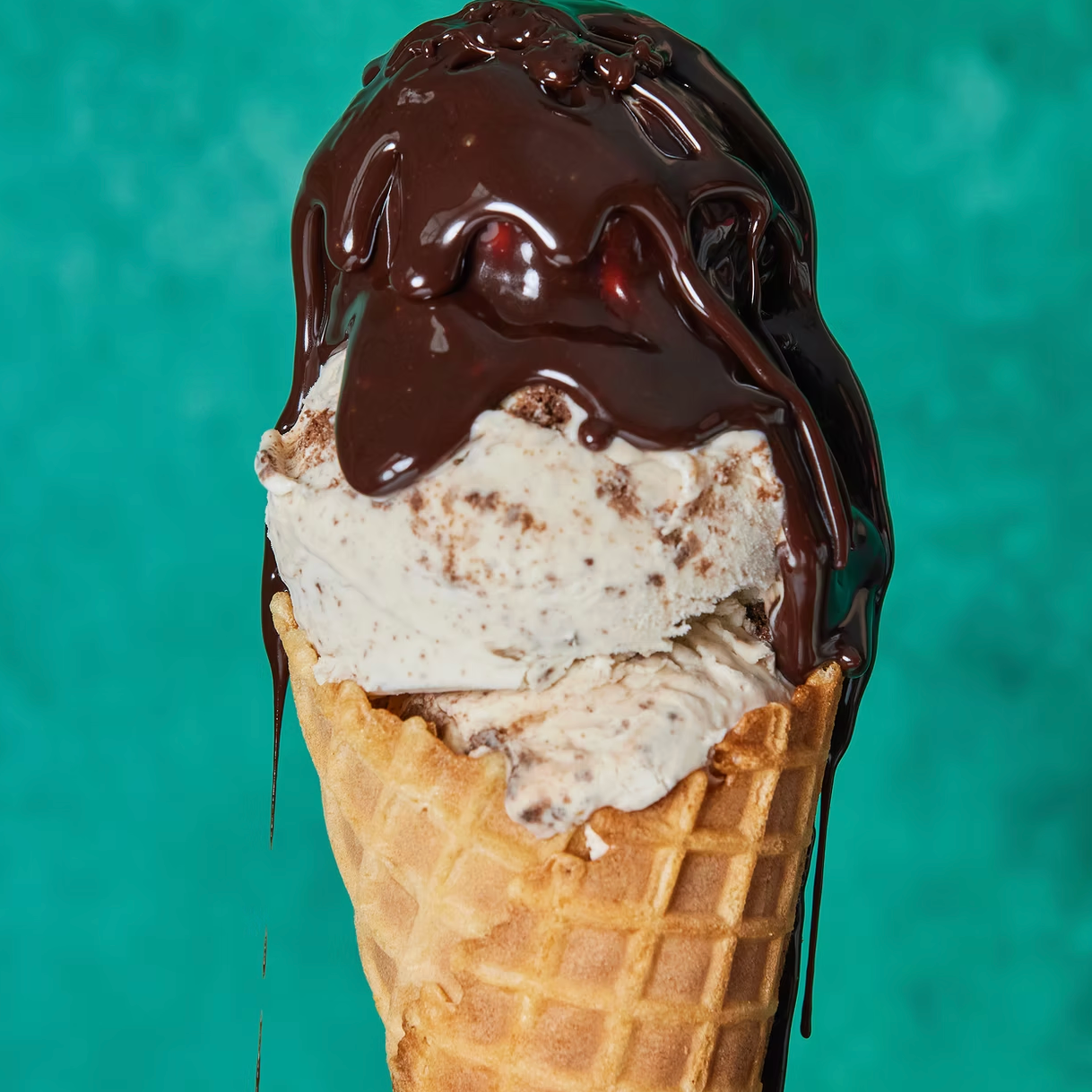 Ice cream cone with chocolate sauce on a teal background