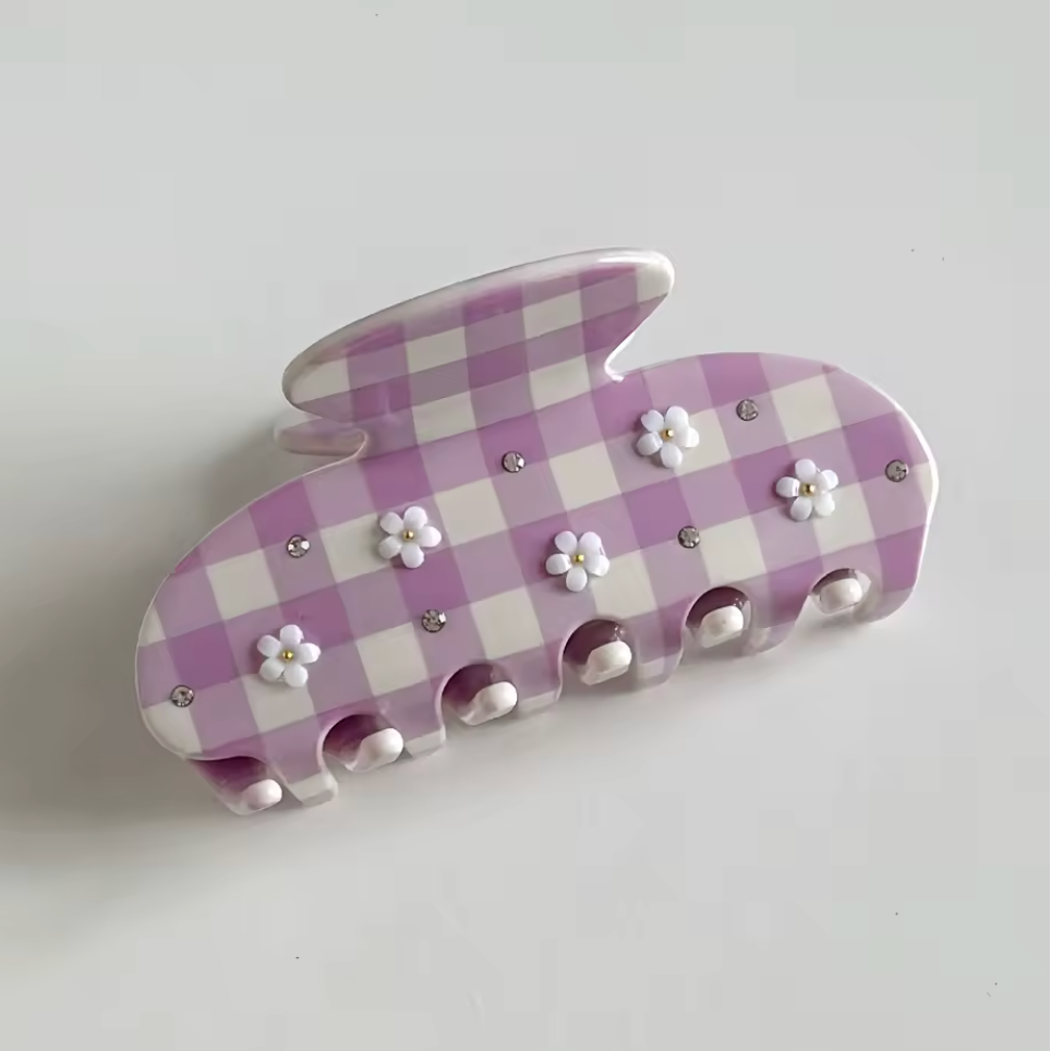 Purple and white checkered hair clip with floral decorations on a light gray background