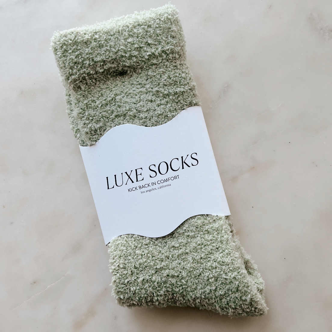 Pair of green luxe socks with a label on a light background
