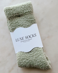 Pair of green luxe socks with a label on a light background