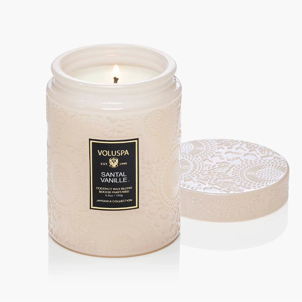 White candle in a textured container with 'Voluspa' label on a white background