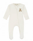 An off-white long-sleeve baby footed sleeper with a small embroidered teddy bear on the chest, shown against a plain white background.