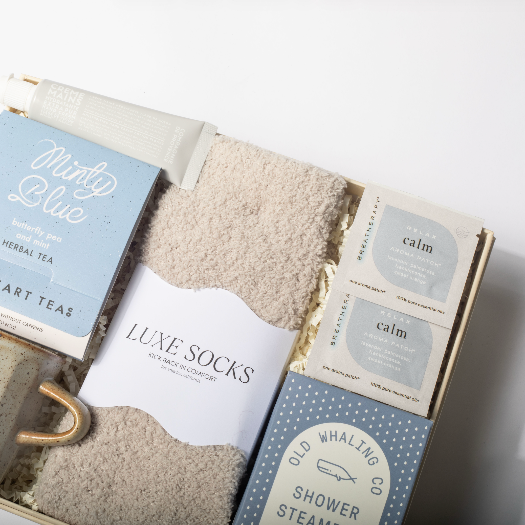 Gift set with mug, tea, socks, and bath steamers in a box on a white background
