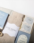 Gift set with mug, tea, socks, and bath steamers in a box on a white background