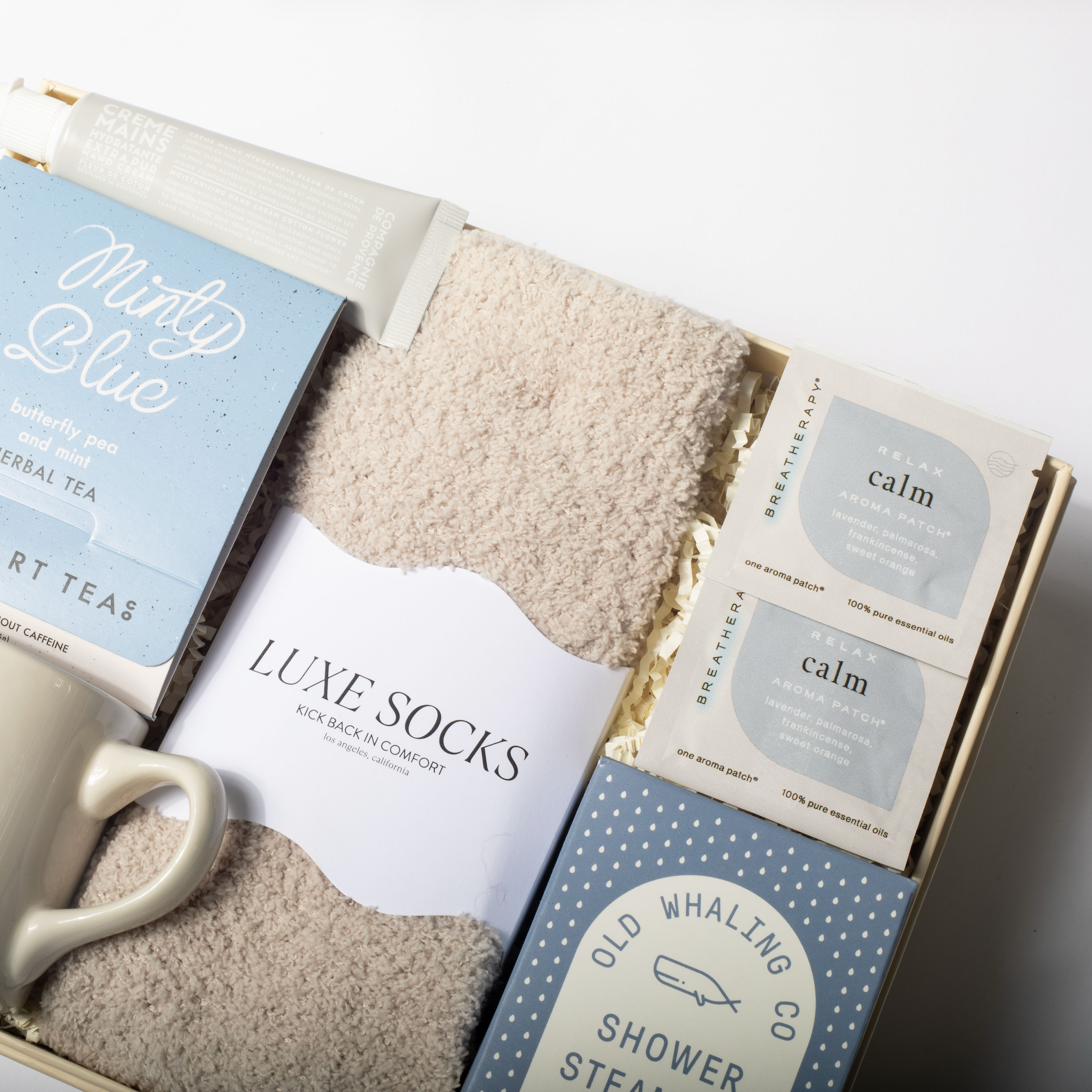 Gift set with mug, tea, socks, and bath items in a box on a white background