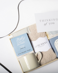 Gift set with mug, soap, and card labeled 'Thinking of You' on a white background