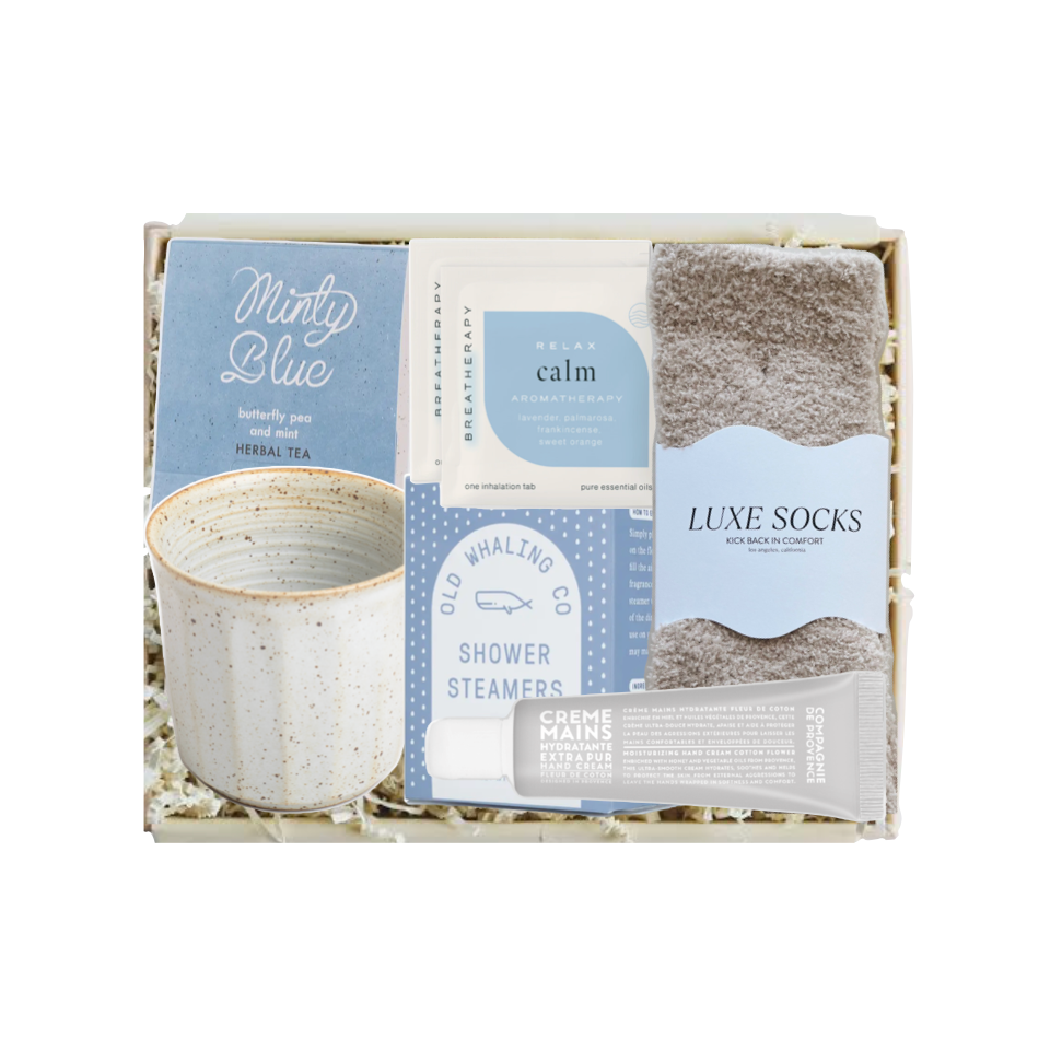 Gift set with tea, socks, and other items in a box on a white background