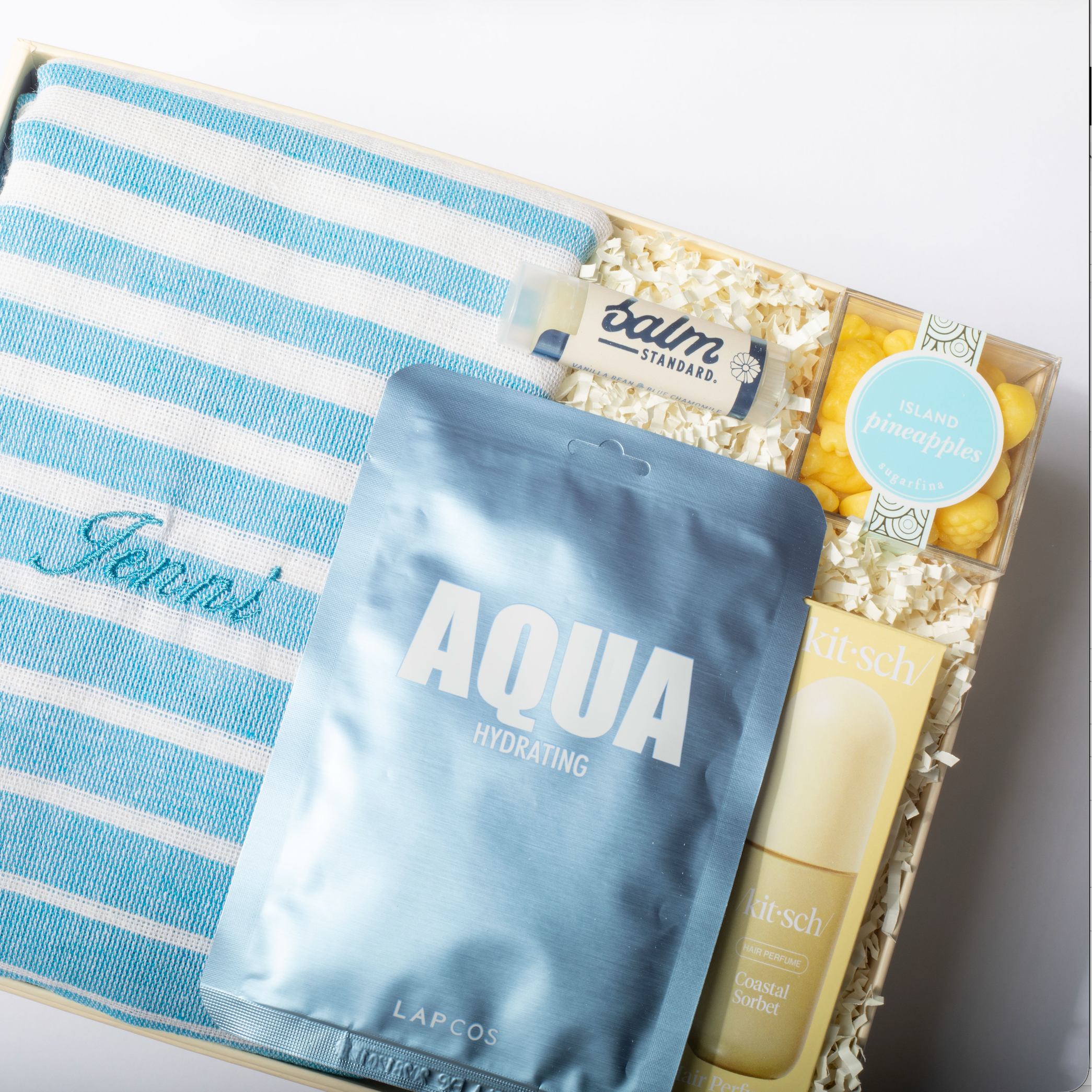 Product set with blue and white striped towel, 'Aqua' package, and other items on a white background