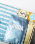 Product set with blue and white striped towel, 'Aqua' package, and other items on a white background