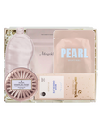 A curated beauty gift set in a white box, featuring a pale pink sleep mask, a pink jar labeled 'SPARKLING FACE GEL', a pink pouch labeled 'PEARL BRIGHTENING', a chocolate bar labeled 'CHOCOLATE', and a small round compact.