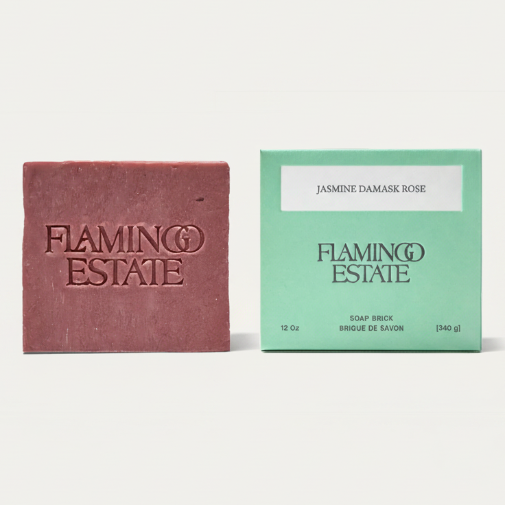 A bar of Flaming Estate soap in a dusty rose color stands next to its mint green packaging box labeled 'Jasmine Damask Rose'.