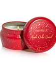 An open red metal candle tin with a matching lid leaning against it on a white background. The lid is printed with the brand name 'capri BLUE' and the scent name 'Apple Cider Social' in gold lettering.
