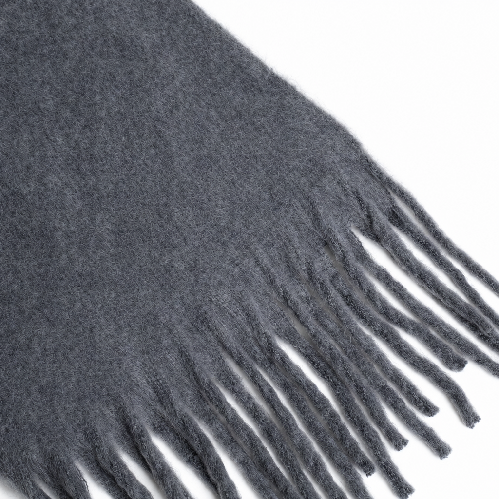 A close-up of a dark gray fuzzy scarf with fringe along one edge, featuring the name 'Tiffany' embroidered in red script on the side.