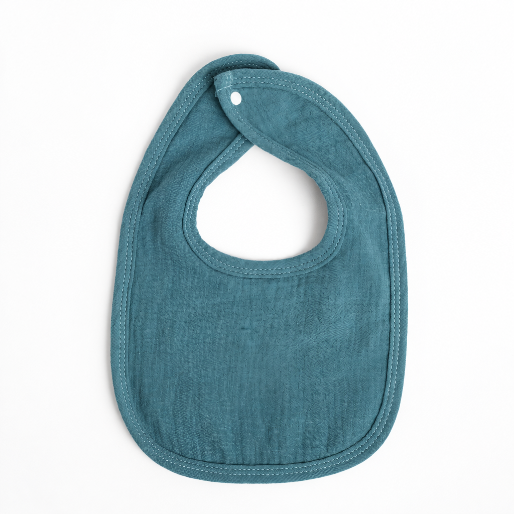 A teal blue muslin baby bib with the name 'Watson' embroidered in white on the front, shown on a clean white background.