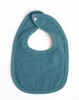 A teal blue muslin baby bib with the name 'Watson' embroidered in white on the front, shown on a clean white background.