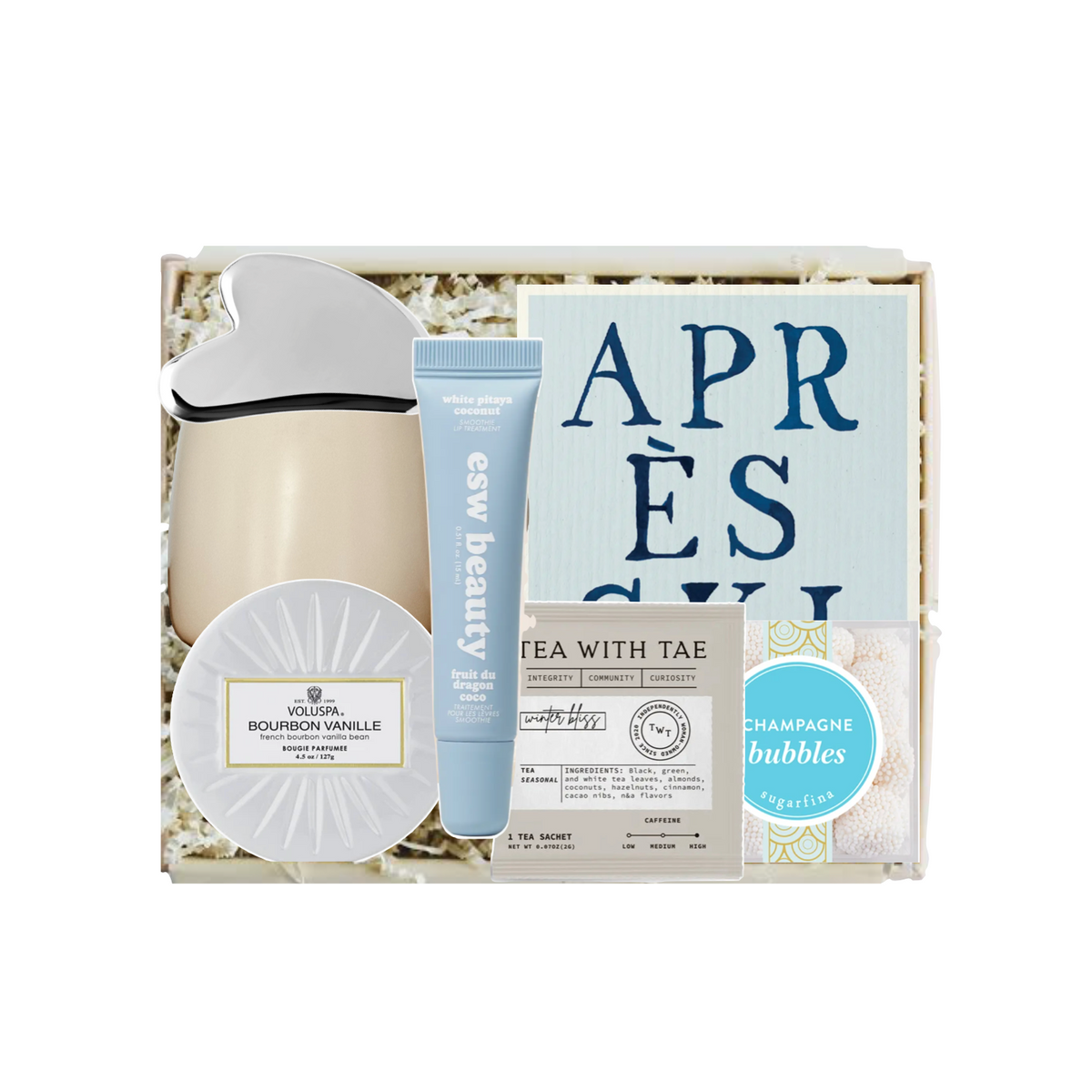 A curated gift box set containing a beige ceramic mug with a white lid, a blue tube of Easy Beauty cream, a round white soap dish, a tea bag packet, and a blue circular sticker, all arranged in white shredded paper inside a light wood box.