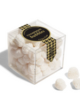 A clear acrylic cube container filled with small white textured gummy candies, tied with a black and gold houndstooth ribbon that reads 'CHAMPAGNE BUBBLES' and 'S. VILLE'.