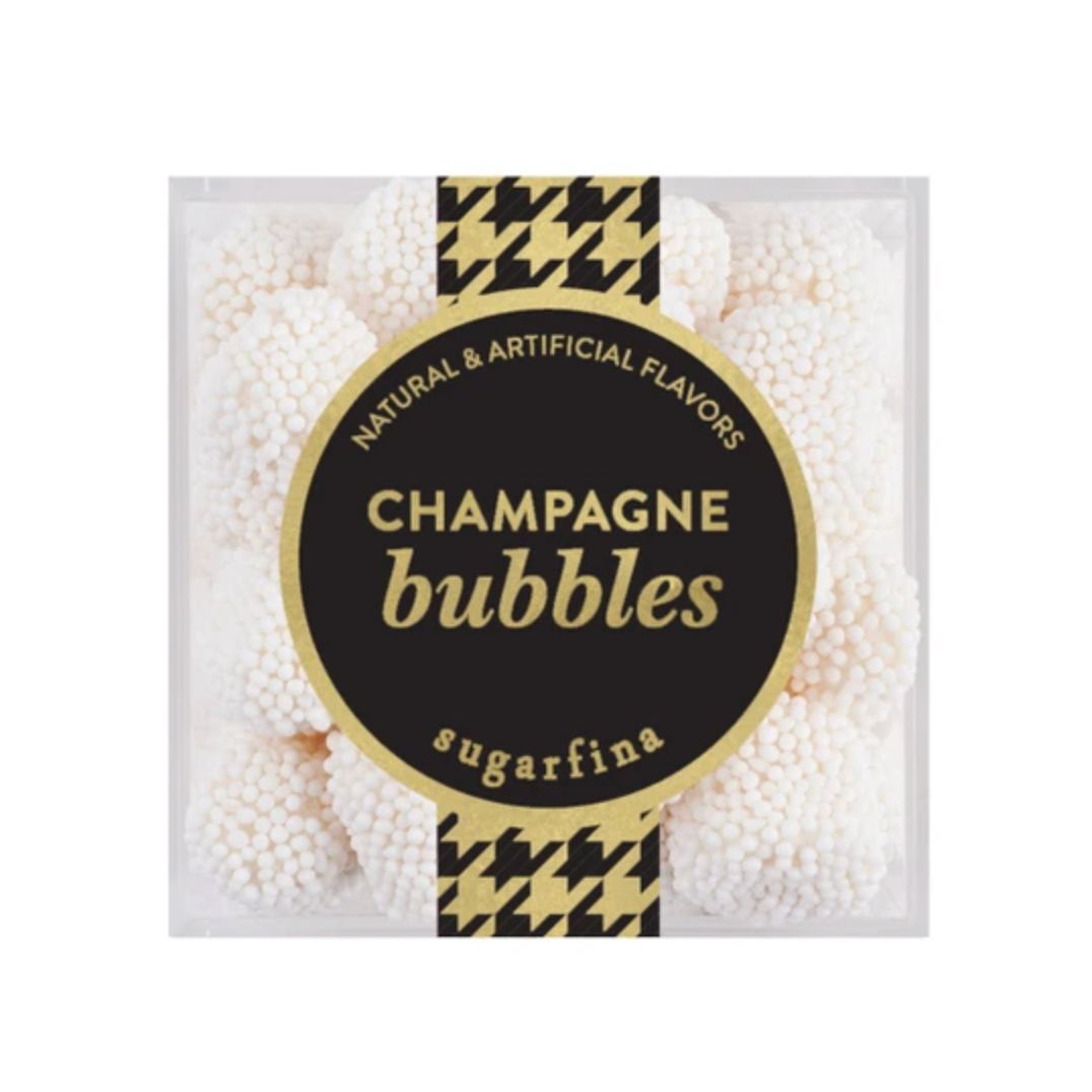 A clear square plastic container filled with white champagne bubbles gum, featuring a large black and gold circular label that reads 'CHAMPAGNE bubbles' and 'sugarfina'.