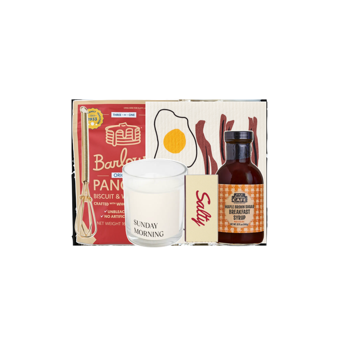 A breakfast-themed gift set from The Breakfast Club, featuring a boxed Pancake Batter mix, a 'Sunday Morning' scented candle, a bottle of Sunday Breakfast Syrup, and a small bag of bacon bits, arranged against a plain white background.
