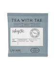 A single tea sachet package for 'Tea With Tae' herbal tea, featuring a muted slate blue-gray color with a white label in the center, set against a plain white background.