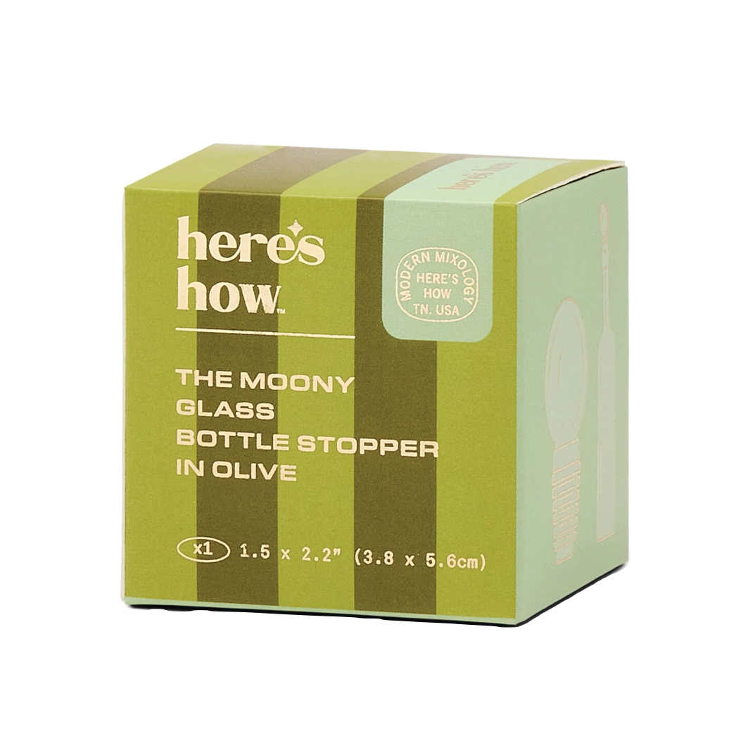 A green and olive striped cardboard box for 'here's how. The Moony Glass Bottle Stopper in Olive', shown on a plain white background.