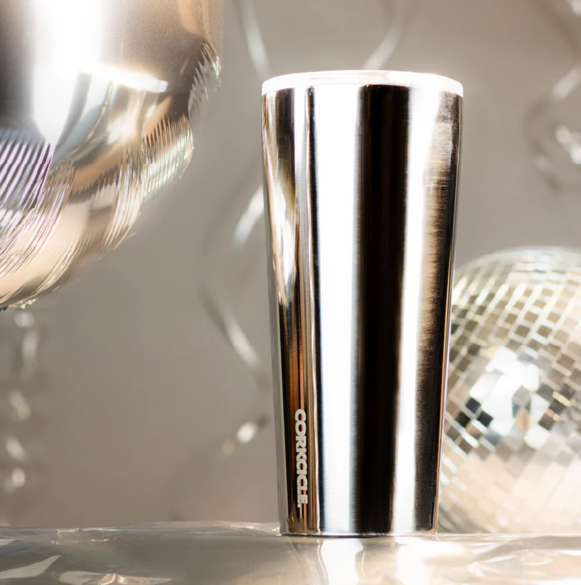 metallic tumbler on silver background with disco ball 