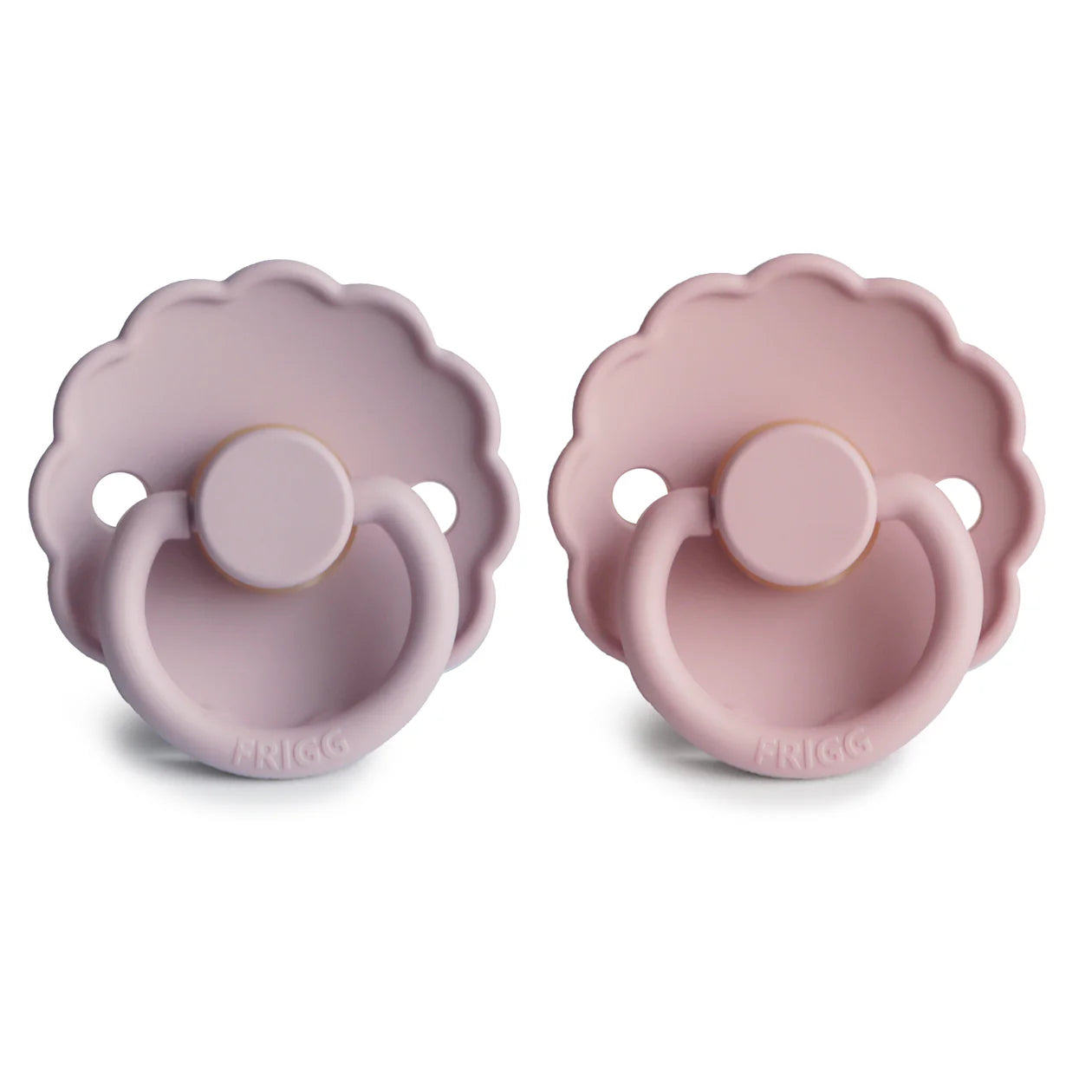 Two FRIGG pacifiers with scalloped edges, displayed side by side—one in soft lilac and the other in baby pink, both suitable for babies.