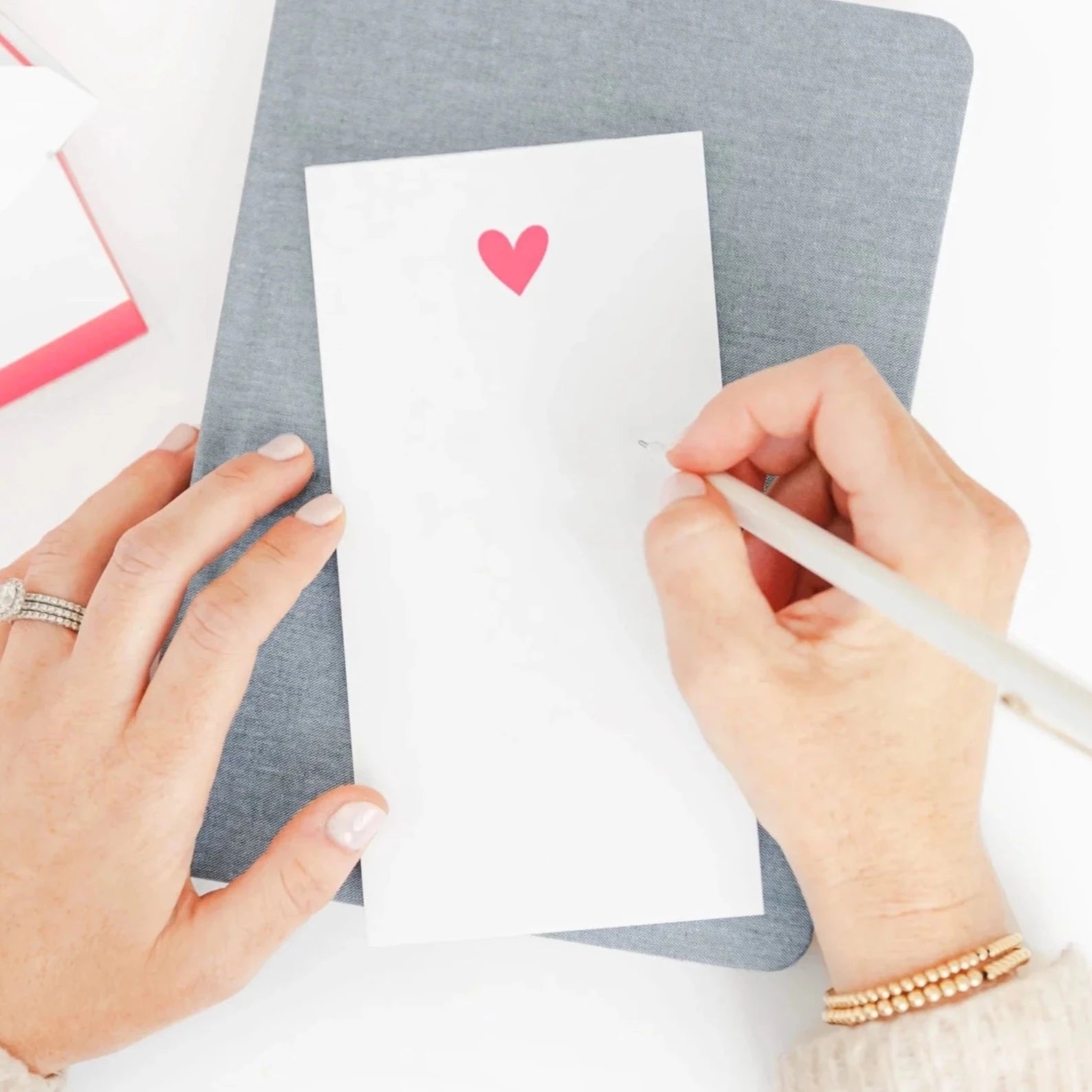 White notepad with neon pink hear on the top center