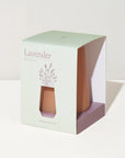 A lavender-scented glass diffuser in a square window box package, with a pale mint green exterior, lavender illustration, and peach-colored glass visible through the front window.