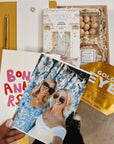 Birthday gift box with photo of two blonde girls and other card held in hand over gift box