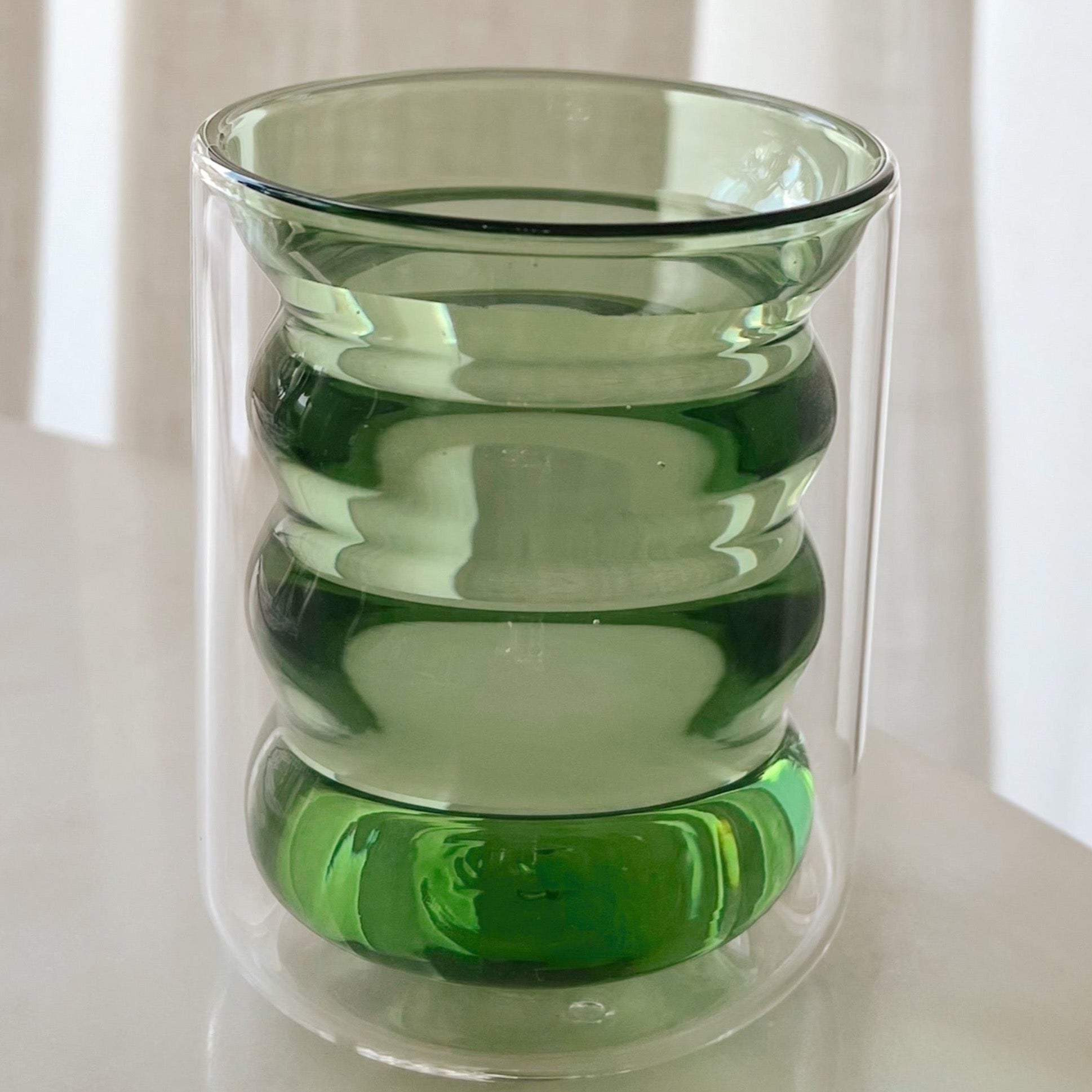 Jade green ripple glass with water on table