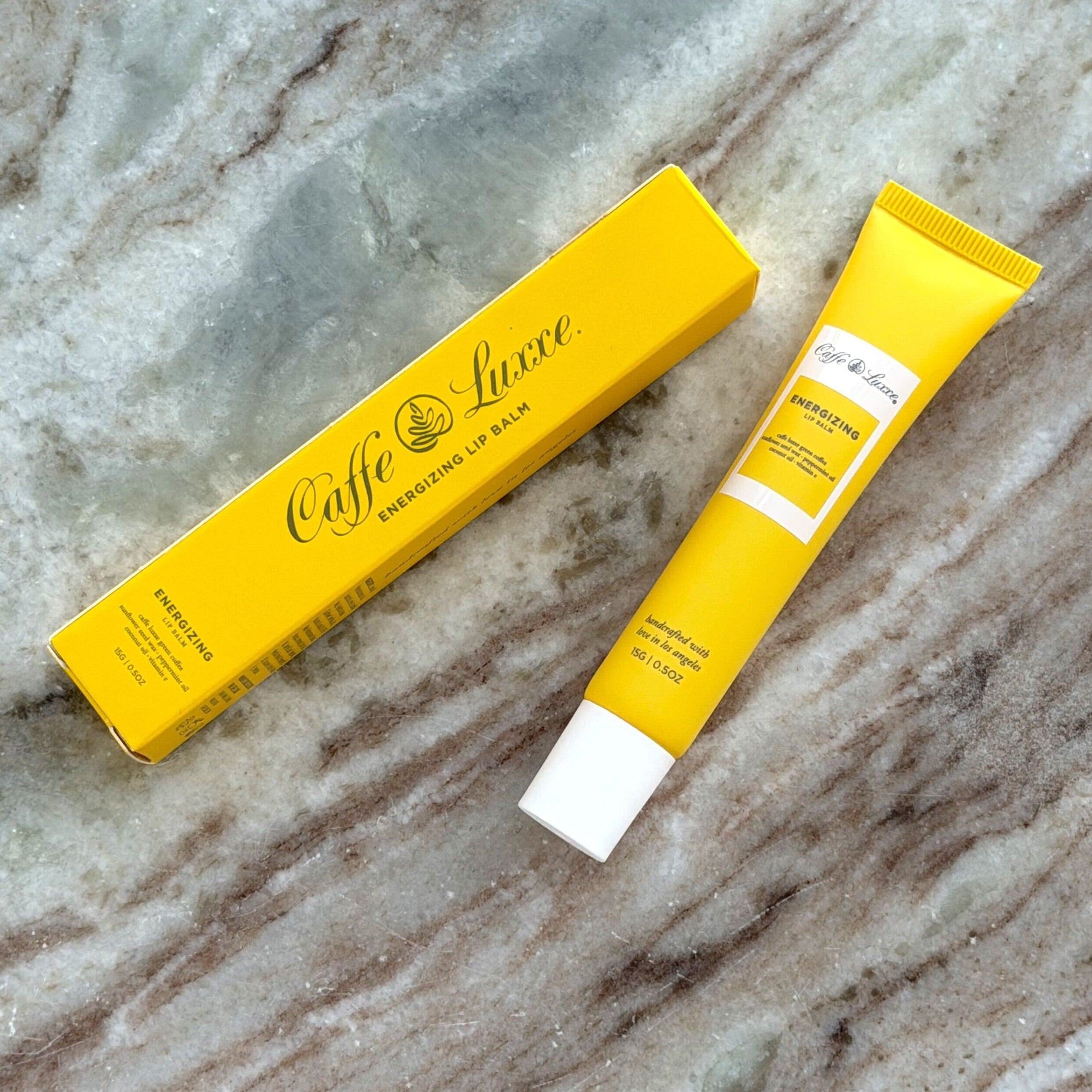 Caffe Luxe lip balm packaging on a marble surface