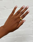 The Stella ring on hand, placed over white brick.
