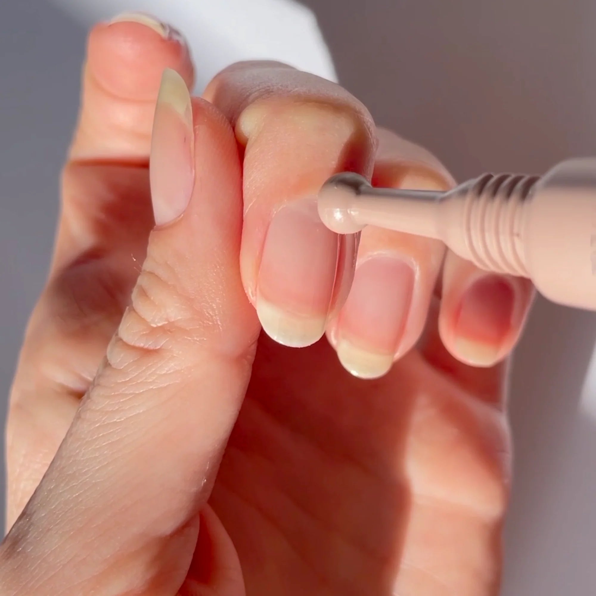Close-up of a hand holding a dental tool against a neutral background