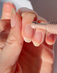 Close-up of a hand holding a dental tool against a neutral background