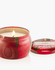 Candle in a decorative red tin with a floral design on a white background