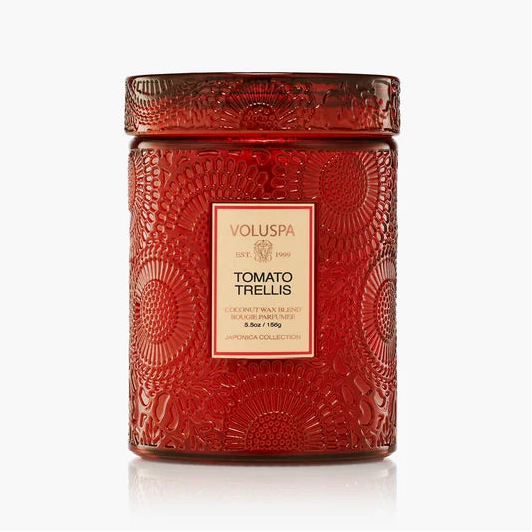 A red textured glass jar candle with a matching lid, featuring a cream-colored label that reads 'VOLUSPA' and 'TOMATO TRELLIS'. The candle is photographed on a clean white background with a subtle reflection underneath.