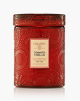A red textured glass jar candle with a matching lid, featuring a cream-colored label that reads 'VOLUSPA' and 'TOMATO TRELLIS'. The candle is photographed on a clean white background with a subtle reflection underneath.