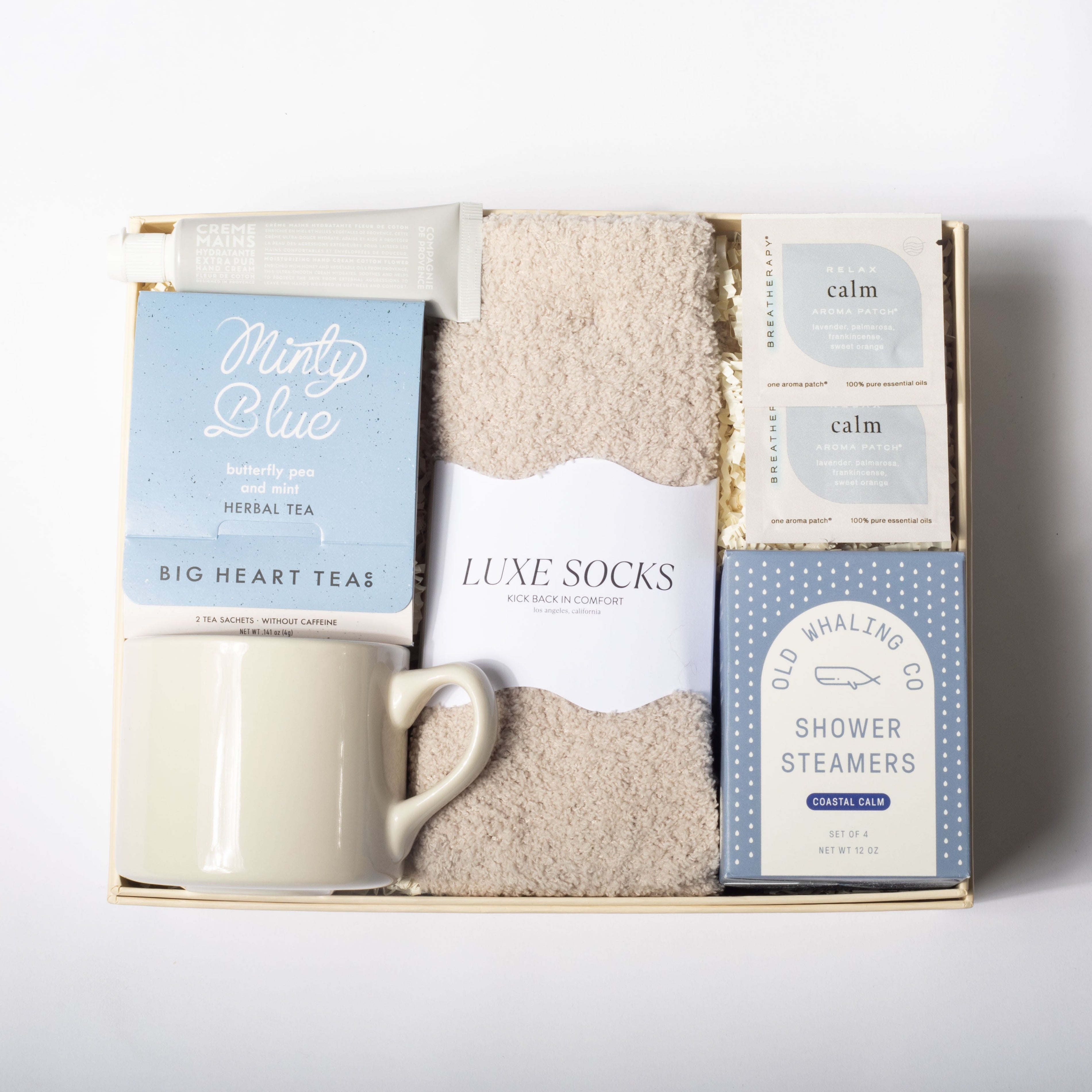 Gift set with mug, tea, socks, and shower steamers on a white background