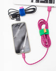 Smartphone with a pink charging cable and USB adapter on a white background