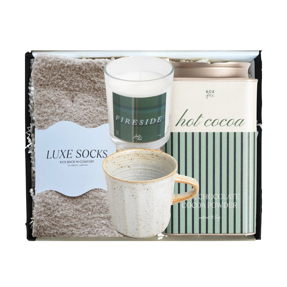 Packaged gift set with mug, candle, and cocoa mix on a white background